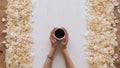 Cup of coffee in hands on table. Rose petals. Flatlay