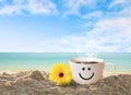 Cup of coffee with happy face on sand beach over blue sky. Royalty Free Stock Photo