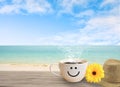 Cup of coffee with happy face on sand beach over blue sky. Royalty Free Stock Photo