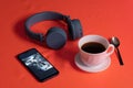 Cup of coffee, headphones and phone on a red table