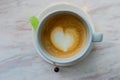 A cup of latte coffee with heart pattern in a white cup on white marble background and green sugar stick Royalty Free Stock Photo