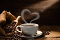 Cup of coffee with heart shape smoke and coffee beans on burlap sack on old wooden background Royalty Free Stock Photo