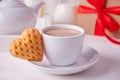 Cup of coffee and a heart shaped cookie with gift box on the white table Royalty Free Stock Photo