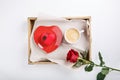 Cup of coffee and heart shaped pink cake on wooden tray. Festive breakfast and red rose on white table. Top view.  Copy space. Royalty Free Stock Photo