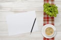 Cup of coffee and indoor plant are on a checkered tablecloth with white paper, pencil next to them. Royalty Free Stock Photo