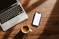 Cup of coffee, laptop computer and smartphone with blank white mockup screen on office work desk Royalty Free Stock Photo