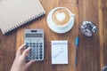 Cup of Coffee latte art Heart shape with office tools on table,hand using calculator Royalty Free Stock Photo