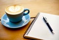 Cup of coffee with latte art on wooden table with notebook. Generative AI Royalty Free Stock Photo