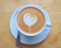 Cup of coffee latte with heart shape and coffee beans on old wooden background Royalty Free Stock Photo