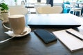 cup of coffee, latte, laptop, phone and notebook for remote distance work on wooden table in cafe Royalty Free Stock Photo