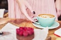 Cup of coffee latte and sweet pastry on wooden table in woman hands. Gentle romantic mood, girl wearing pink skirt.