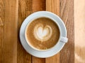 A cup of coffee latte on a wooden table. A mug of flat white coffee on a wooden background. Coffee art. Heart flower Royalty Free Stock Photo
