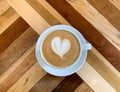 A cup of coffee latte on a wooden table. A mug of flat white coffee on a wooden background. Coffee art. Heart flower Royalty Free Stock Photo