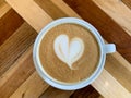 A cup of coffee latte on a wooden table. A mug of flat white coffee on a wooden background. Coffee art. Heart flower Royalty Free Stock Photo