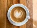 A cup of coffee latte on a wooden table. A mug of flat white coffee on a wooden background. Coffee art. Heart flower Royalty Free Stock Photo