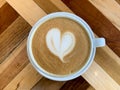 A cup of coffee latte on a wooden table. A mug of flat white coffee on a wooden background. Coffee art. Heart flower Royalty Free Stock Photo