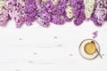 Cup of coffee and lilac flowers border on white wooden background. Copy space, top view. Royalty Free Stock Photo