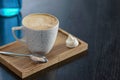 Cup of coffee on the little board over black background. Latte art. Little coffee mug and spoon.