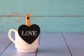 Cup of coffee and little heart shape chalkboard with the word: LOVE.