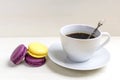 Cup of coffee with macaron on white wooden background from above, flat lay