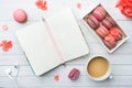 Cup of coffee, macaroon cookies in a box, flowers and a notebook on a white background. copy space. concept beautiful Breakfast.