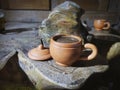 A cup of coffee made from clay on a wooden table made from teak wood roots