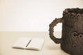 Cup of coffee made up of letters on a wooden table with diary an