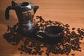 Cup of coffee and coffee maker moka pot with roasted coffee beans on wooden table. Royalty Free Stock Photo