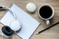 A cup of coffee with marshmallow, notebook with pencil and white headphones on wooden background. Cosy workspace. Top view, flat Royalty Free Stock Photo