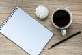 A cup of coffee with marshmallow, notebook with pencil on wooden background. Cosy workspace. Top view, flat lay Royalty Free Stock Photo