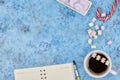 Cup with coffee and marshmallows, blank open notebook with pen on abstract blue background. Top view. Flat mockup. space for text Royalty Free Stock Photo