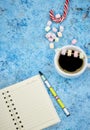 Cup with coffee and marshmallows, blank open notebook with pen on abstract blue background. Top view. Flat mockup. space for text Royalty Free Stock Photo