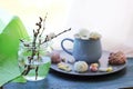 A cup of coffee, meringues, a bouquet of flowering branches of a cherry tree on a windowsill