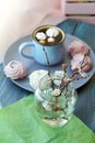 A cup of coffee, meringues, a bouquet of flowering branches of a cherry tree on a windowsill