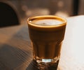 A cup of coffee with milk on a brown wooden table