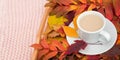 Cup of coffee with milk and colorful leaves on wood tray on pink pastel knitted plaid background. Autumn cozy. Flat lay, top view Royalty Free Stock Photo