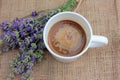 Cup of coffee with milk and lavender flowers on burlap fabric texture with copy space. Royalty Free Stock Photo