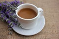 Cup of coffee with milk and lavender flowers on burlap fabric texture with copy space. Royalty Free Stock Photo
