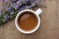 Cup of coffee with milk and lavender flowers on burlap fabric texture with copy space. Royalty Free Stock Photo