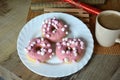 Cup of coffee with milk and three donuts with pink icing on a white plate. Royalty Free Stock Photo