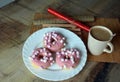 Cup of coffee with milk and three donuts with pink icing on a white plate. Royalty Free Stock Photo