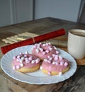 Cup of coffee with milk and three donuts with pink icing on a white plate. Royalty Free Stock Photo