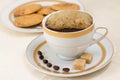 Cup of coffee with more cream and biscuits on background