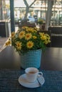 Cup of coffee in the morning, flowers on the table and the city waking up