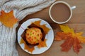 Cup of coffee, muffin, scarf with autumn leaves close-up