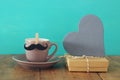 Cup of coffee with mustache next to gift box and wooden heart. Father& x27;s day concept Royalty Free Stock Photo