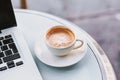 Cup of coffee near laptop computer in cafe