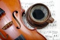 A cup of coffee, neck of violin and notes. top view