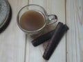 A cup of coffee next to the fingers of chocolate yellow roses Photography Night Wood background