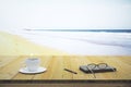 Cup of coffee notebook and glasses on a wooden table on the beach Royalty Free Stock Photo